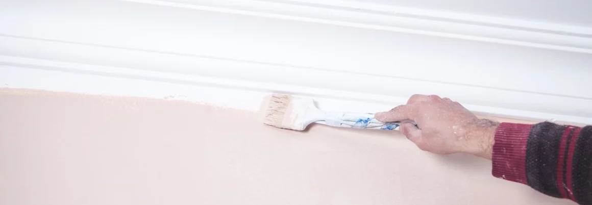 Mann, der mit einem Pinsel eine Wand streicht.